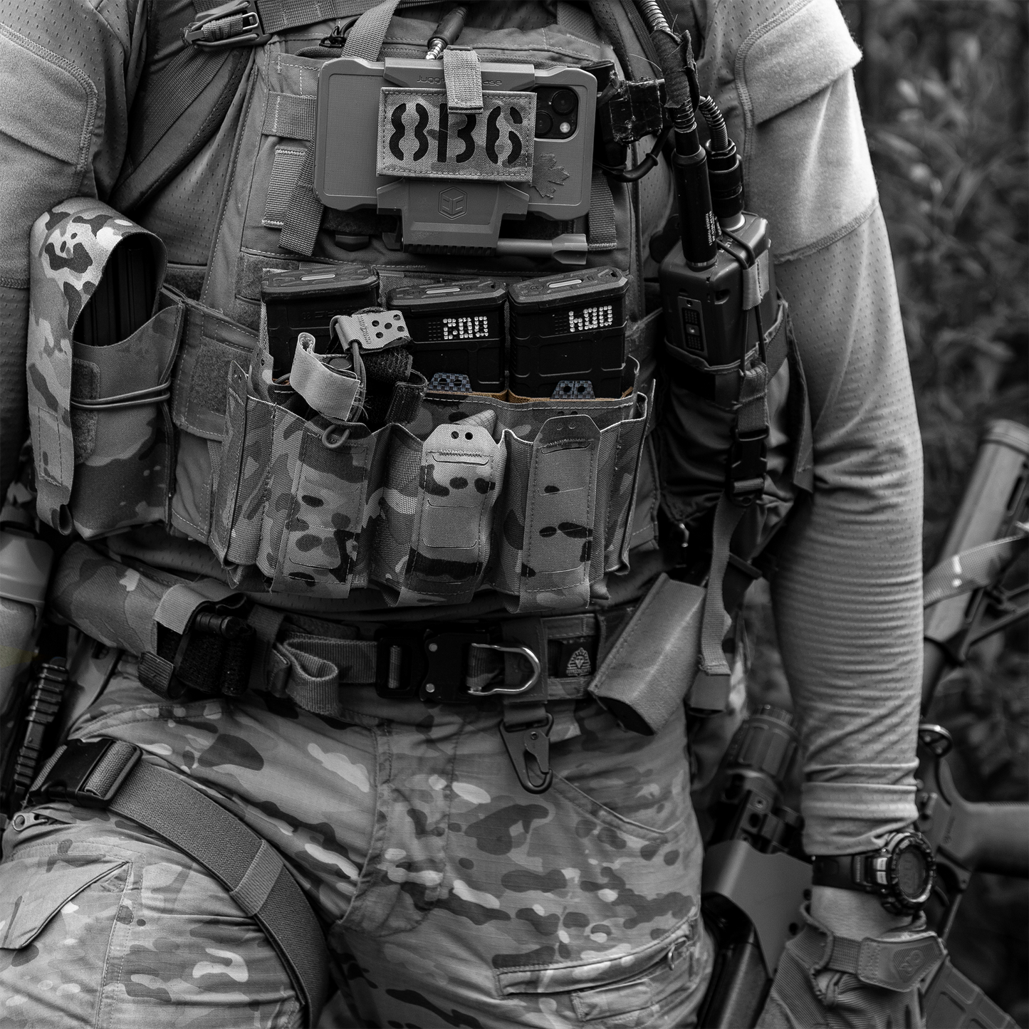 Person wearing a tactical vest with various equipment and a patch