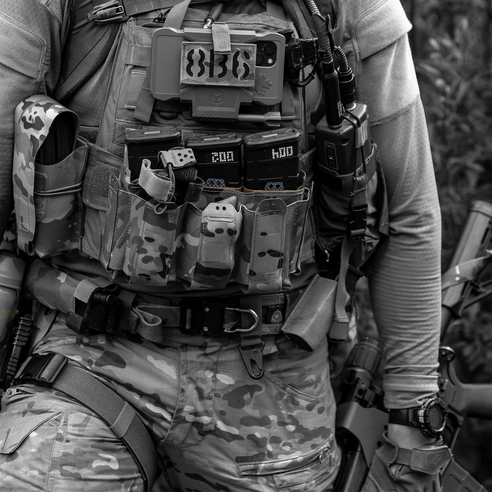 Person wearing a tactical vest with various equipment and a patch
