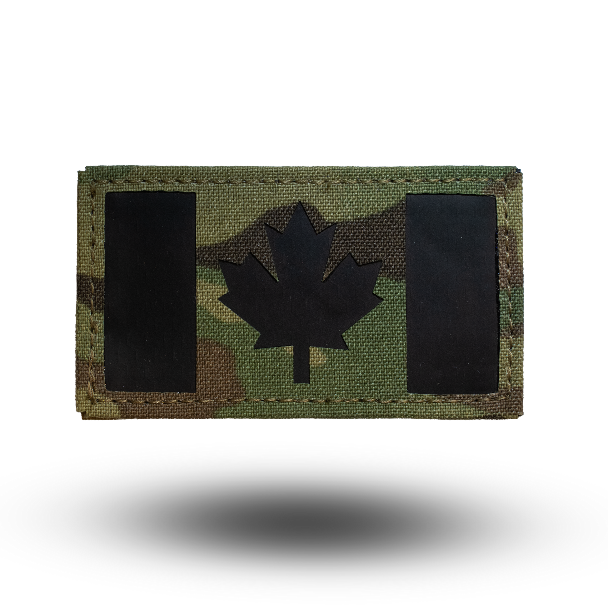 Multicam patterned patch with black maple leaf design on a white background